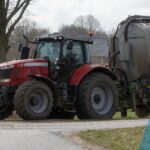 Boer rijdt een tractor met mest.